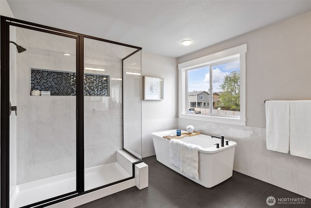bathroom featuring a freestanding bath, tile walls, tile patterned flooring, and a stall shower