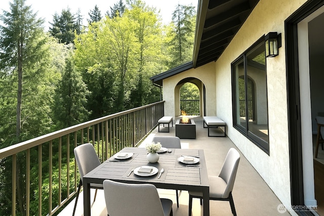 balcony with an outdoor fire pit, a patio area, and outdoor dining area