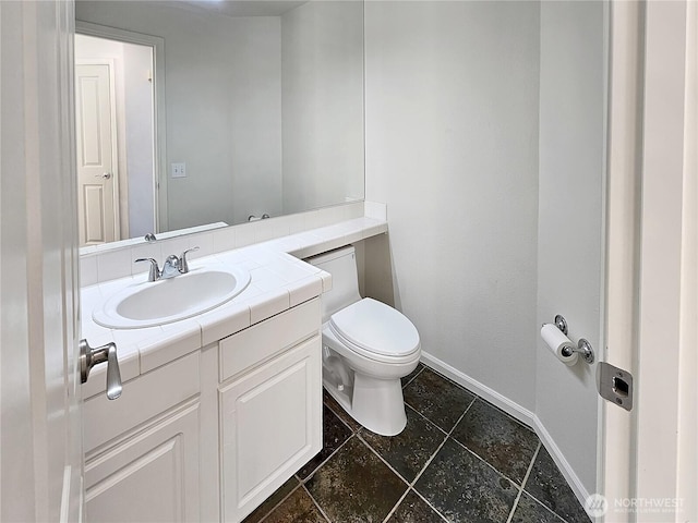 bathroom with baseboards, toilet, and vanity