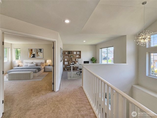 corridor featuring light colored carpet, plenty of natural light, and a chandelier