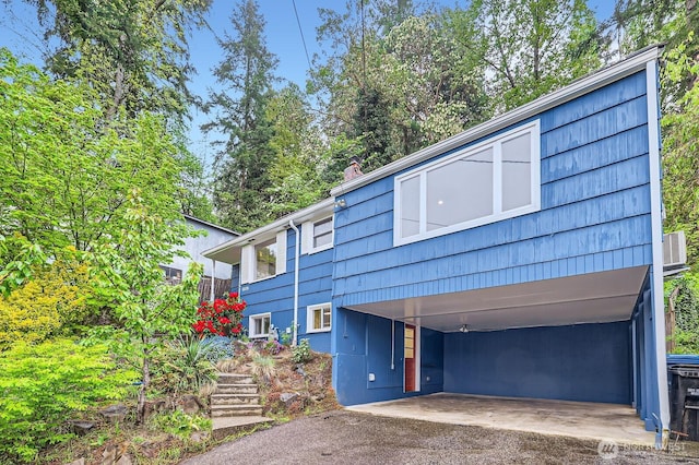view of front of property featuring central AC, driveway, stairs, and a carport