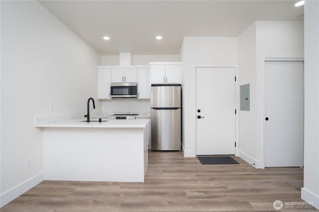 2420 S I St Unit 12, Tacoma, WA 98405 - kitchen featuring a sink, electric panel, stainless steel appliances, light countertops, and a peninsula