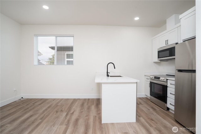 2420 S I St Unit 12, Tacoma, WA 98405 - kitchen featuring light wood finished floors, white cabinets, a sink, and appliances with stainless steel finishes