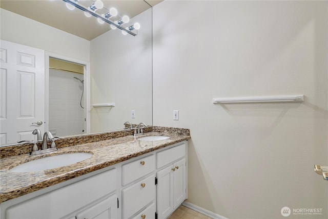 full bathroom with a sink, baseboards, walk in shower, and double vanity