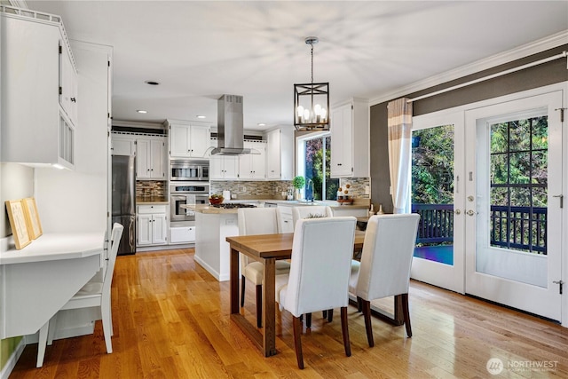 dining area featuring crown molding, a chandelier, and light wood-style floors