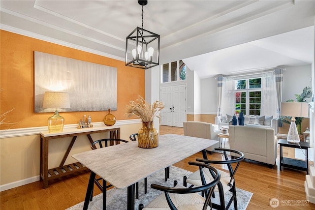 dining space featuring an inviting chandelier, wood finished floors, and a raised ceiling