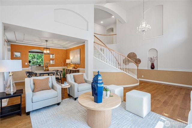 living room with an inviting chandelier, arched walkways, stairs, and wood finished floors
