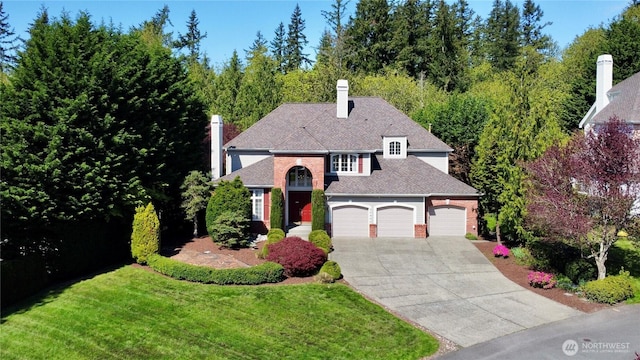 traditional home with an attached garage, brick siding, a front yard, a chimney, and driveway