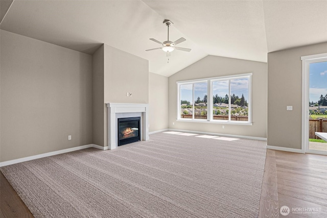 9621 7th Ave SE, Lacey, WA 98513 - unfurnished living room featuring a ceiling fan, healthy amount of natural light, a glass covered fireplace, vaulted ceiling, and light wood-style flooring