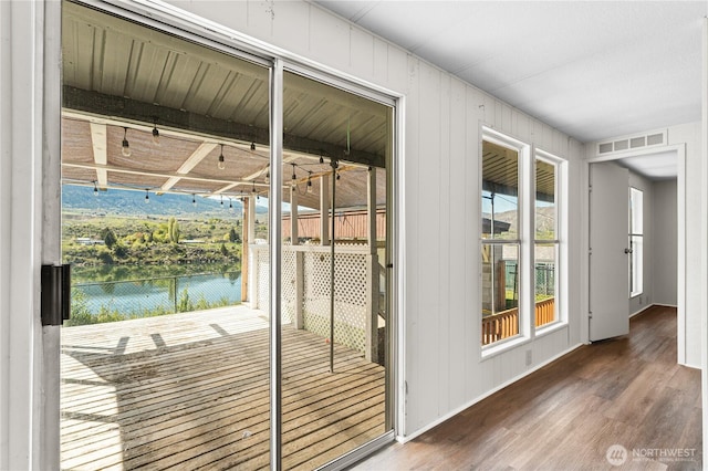 doorway to outside featuring wood finished floors, visible vents, a water view, and a healthy amount of sunlight