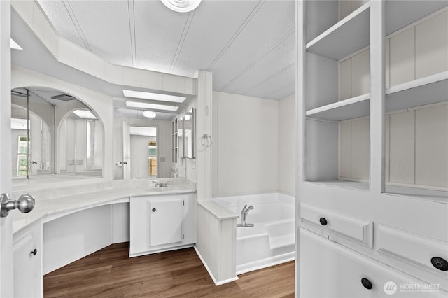 full bathroom featuring a bath, vanity, wood finished floors, and a textured ceiling