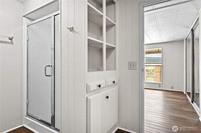 bathroom with baseboards, wood finished floors, and a stall shower