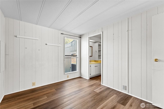 unfurnished bedroom featuring a textured ceiling, a sink, wood finished floors, a decorative wall, and ensuite bath