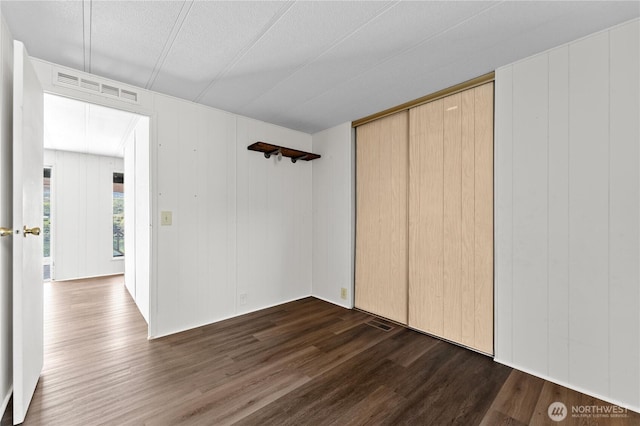 unfurnished bedroom featuring visible vents, a textured ceiling, dark wood-style floors, and a closet