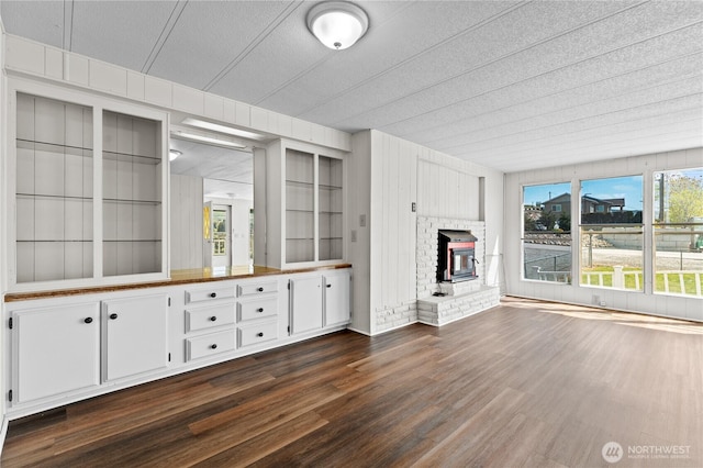 unfurnished living room with dark wood-style flooring, a textured ceiling, and a fireplace