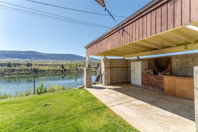view of dock featuring fence, a lawn, and a water and mountain view
