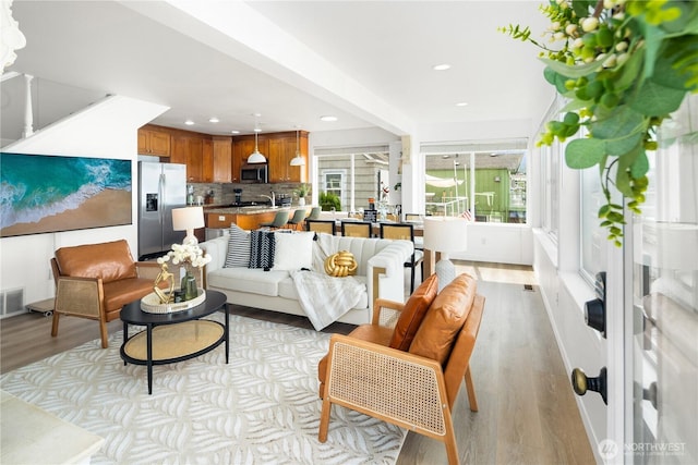 living room with recessed lighting, light wood-style flooring, and visible vents