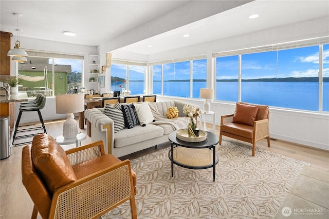 living room with recessed lighting, light wood-style flooring, and a water view