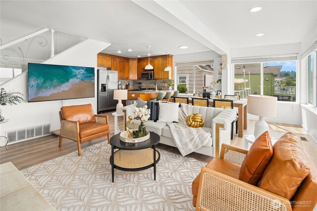 living room featuring visible vents, recessed lighting, light wood-style floors, and plenty of natural light