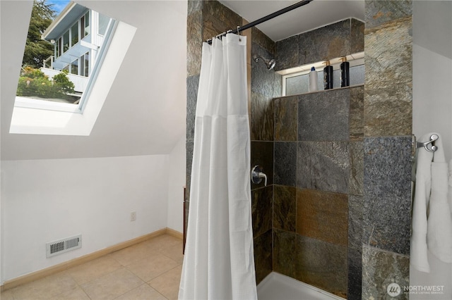 full bathroom featuring visible vents, tile patterned flooring, baseboards, tiled shower, and a skylight