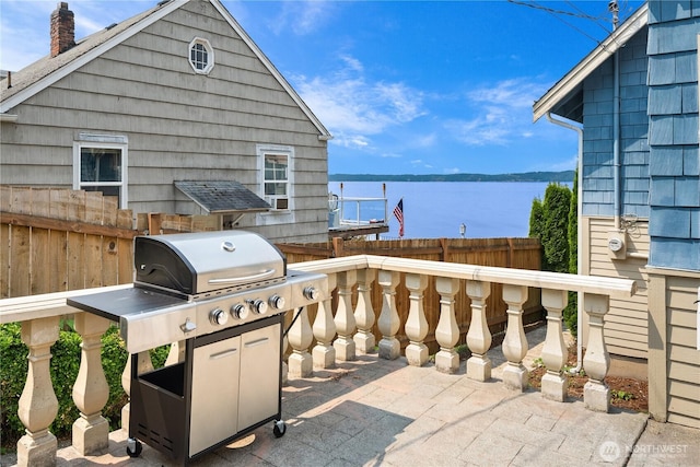 view of patio with fence and a water view