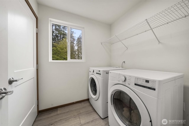laundry area with light wood-type flooring, baseboards, washer and dryer, and laundry area