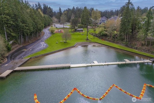 birds eye view of property featuring a water view and a wooded view