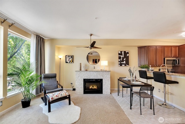 225 Logan Ave S Unit 205, Renton, WA 98057 - living area with baseboards, a tiled fireplace, ceiling fan, and light colored carpet