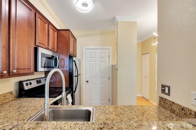 225 Logan Ave S Unit 205, Renton, WA 98057 - kitchen with light stone countertops, brown cabinetry, a sink, crown molding, and stainless steel appliances