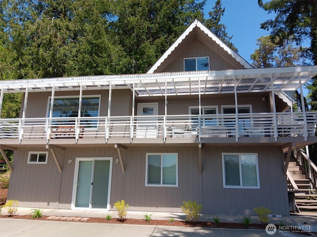 rear view of property featuring stairs and a balcony