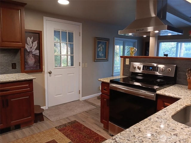 kitchen with wall chimney range hood, decorative backsplash, a wealth of natural light, and stainless steel range with electric stovetop