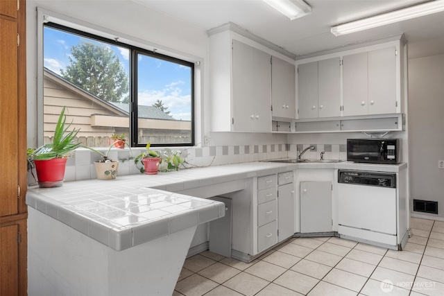 kitchen featuring a sink, tile countertops, black microwave, dishwasher, and visible vents