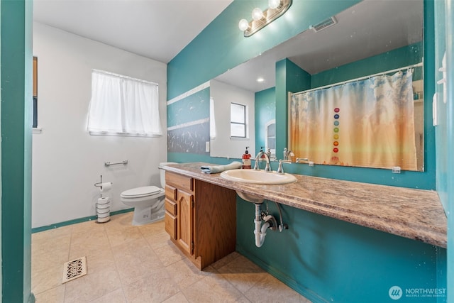 bathroom with toilet, vanity, and visible vents