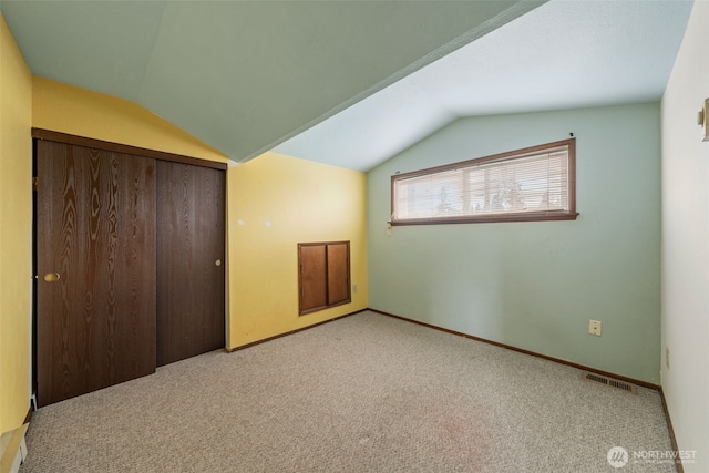 unfurnished bedroom featuring vaulted ceiling, visible vents, and carpet floors