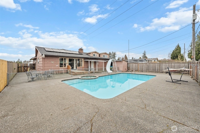 view of pool featuring a shed, a fenced backyard, a patio, an in ground hot tub, and a water slide