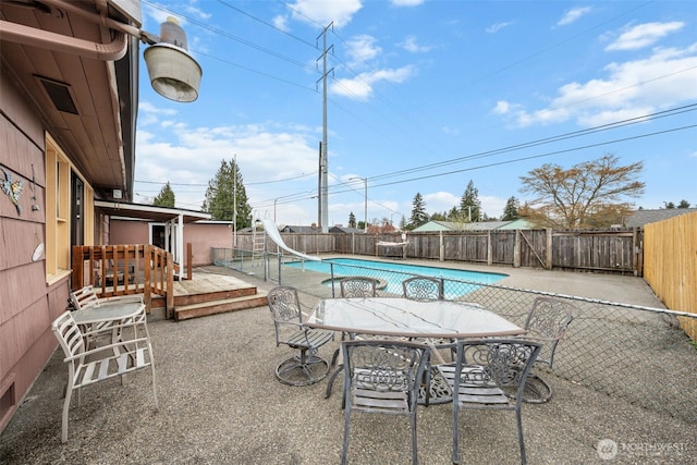 view of pool featuring a water slide, a wooden deck, a fenced in pool, and a fenced backyard