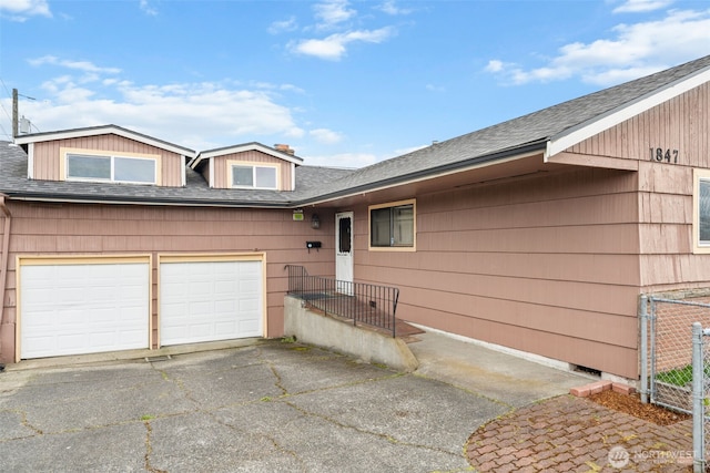 view of front of property with driveway, fence, and roof with shingles