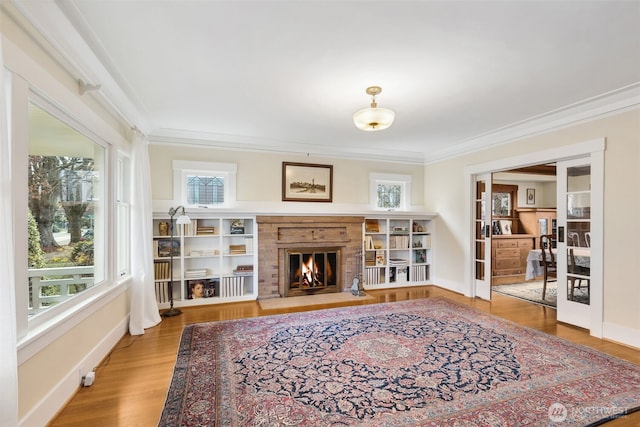 sitting room with baseboards, a fireplace with flush hearth, ornamental molding, and wood finished floors
