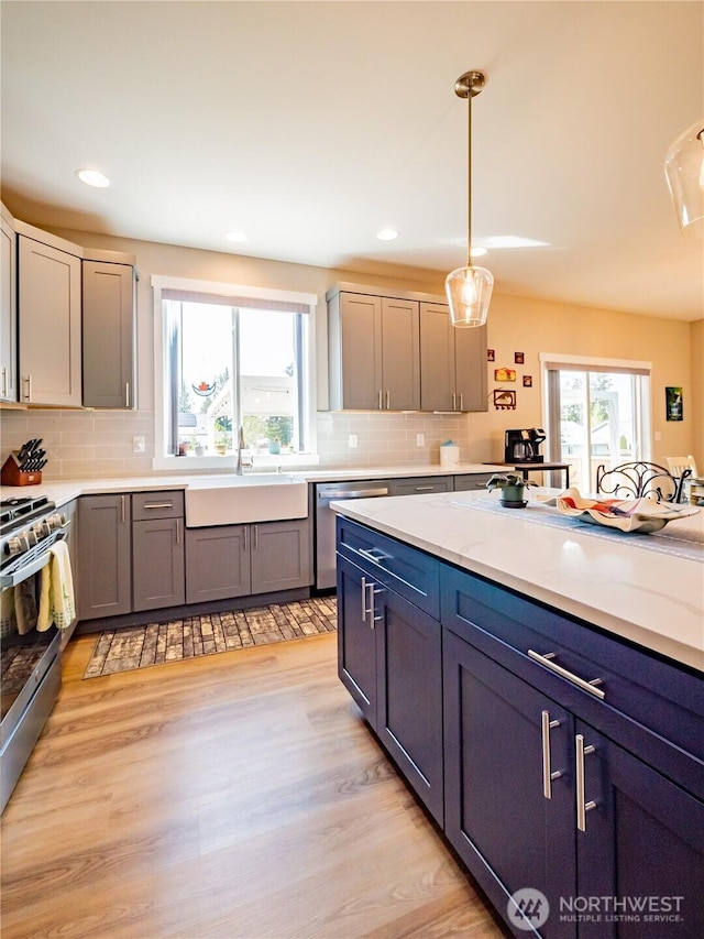 806 Cody St SE, Rainier, WA 98576 - kitchen with a sink, appliances with stainless steel finishes, light countertops, backsplash, and decorative light fixtures