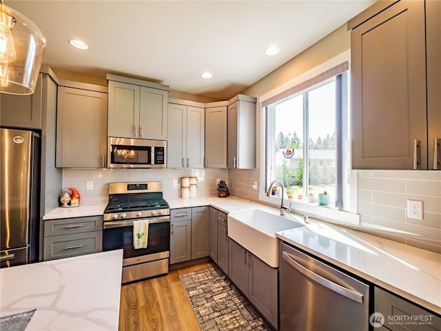 806 Cody St SE, Rainier, WA 98576 - kitchen with appliances with stainless steel finishes, a sink, gray cabinets, backsplash, and light stone counters