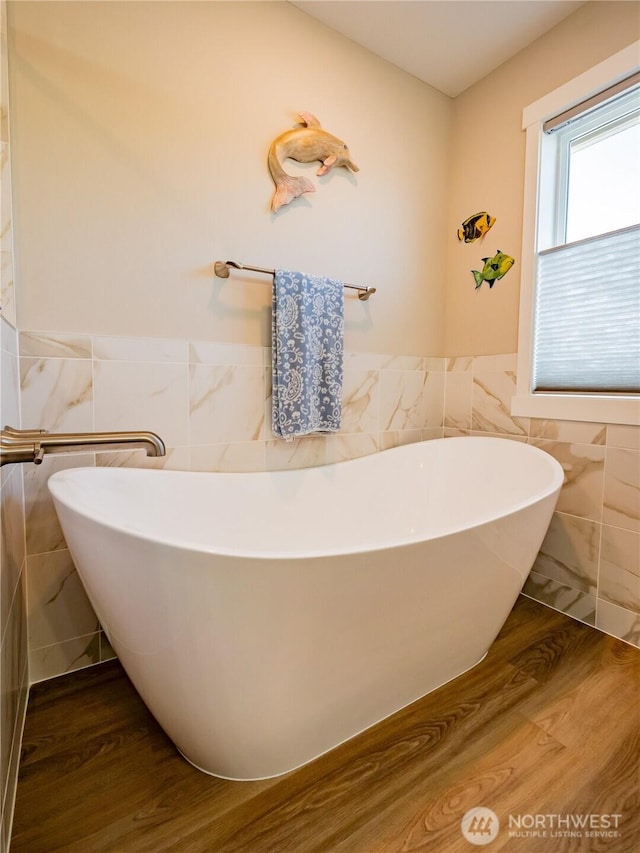 806 Cody St SE, Rainier, WA 98576 - bathroom with tile walls, a freestanding bath, wainscoting, and wood finished floors