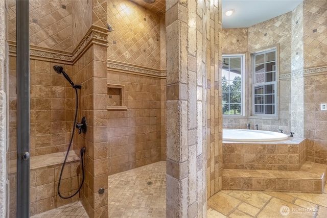 full bath with tile walls, a tile shower, a garden tub, and stone tile flooring