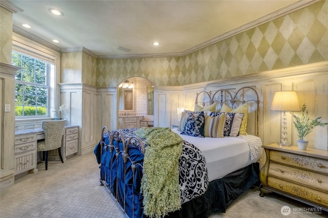 bedroom featuring crown molding, built in desk, light colored carpet, wallpapered walls, and arched walkways