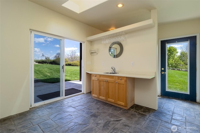 doorway to outside with recessed lighting, a skylight, a sink, and stone tile flooring
