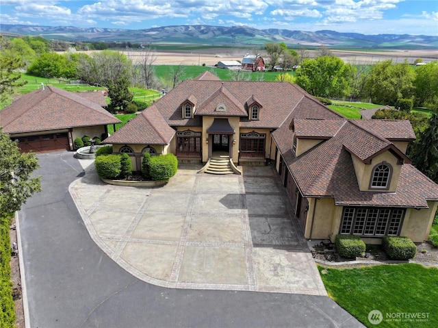 view of front of property featuring a shingled roof, a mountain view, stucco siding, and driveway