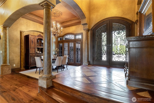 foyer entrance featuring decorative columns, arched walkways, french doors, and a towering ceiling