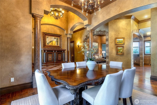 dining area with a notable chandelier, decorative columns, ornamental molding, a towering ceiling, and arched walkways