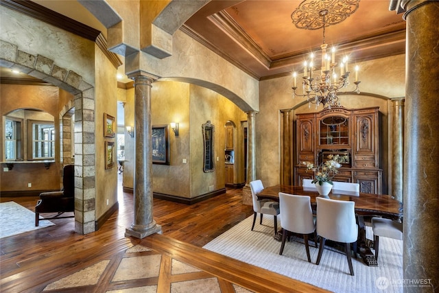 dining area with decorative columns, hardwood / wood-style floors, crown molding, and arched walkways