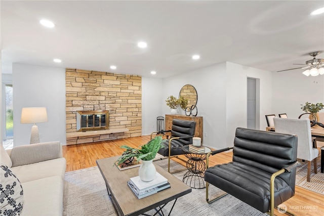 living area with ceiling fan, recessed lighting, light wood finished floors, and a stone fireplace