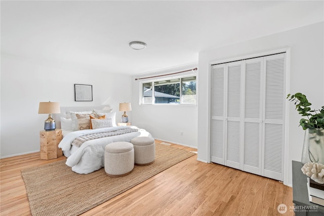 bedroom with baseboards, visible vents, wood finished floors, and a closet